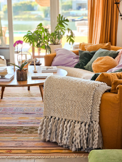 FLAMA HERITAGE THROW in Beige - Draped over a sofa in a brightly lit living room