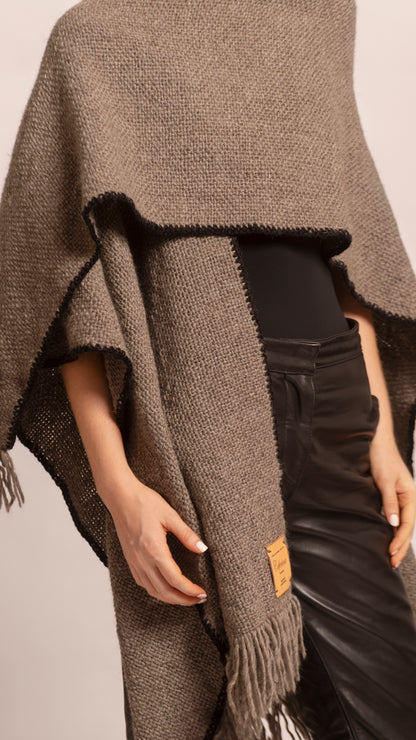 ORIGEN RUANA in Vison (Taupe) - Close-up of the leather branding tag and woven wool texture.